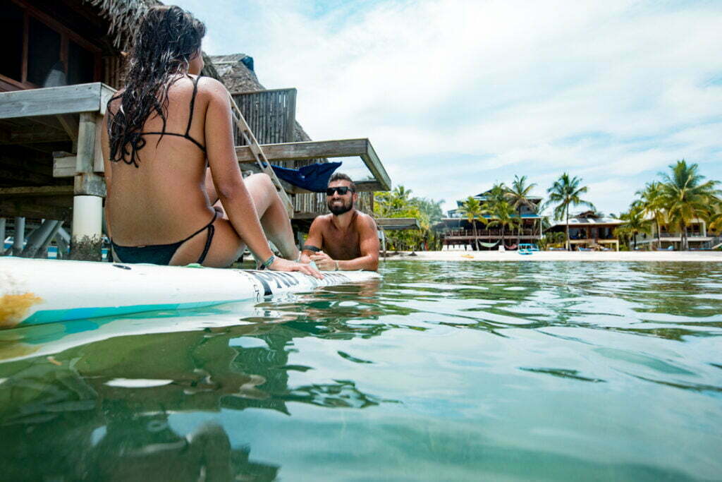 A man and woman sitting on surfboards in the water.