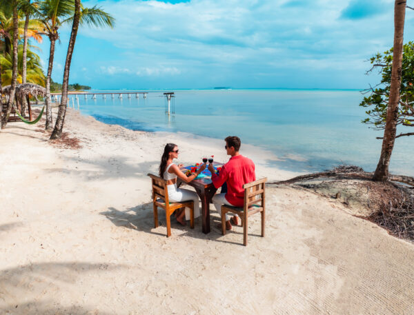 A man and woman sitting at a table on the beach.